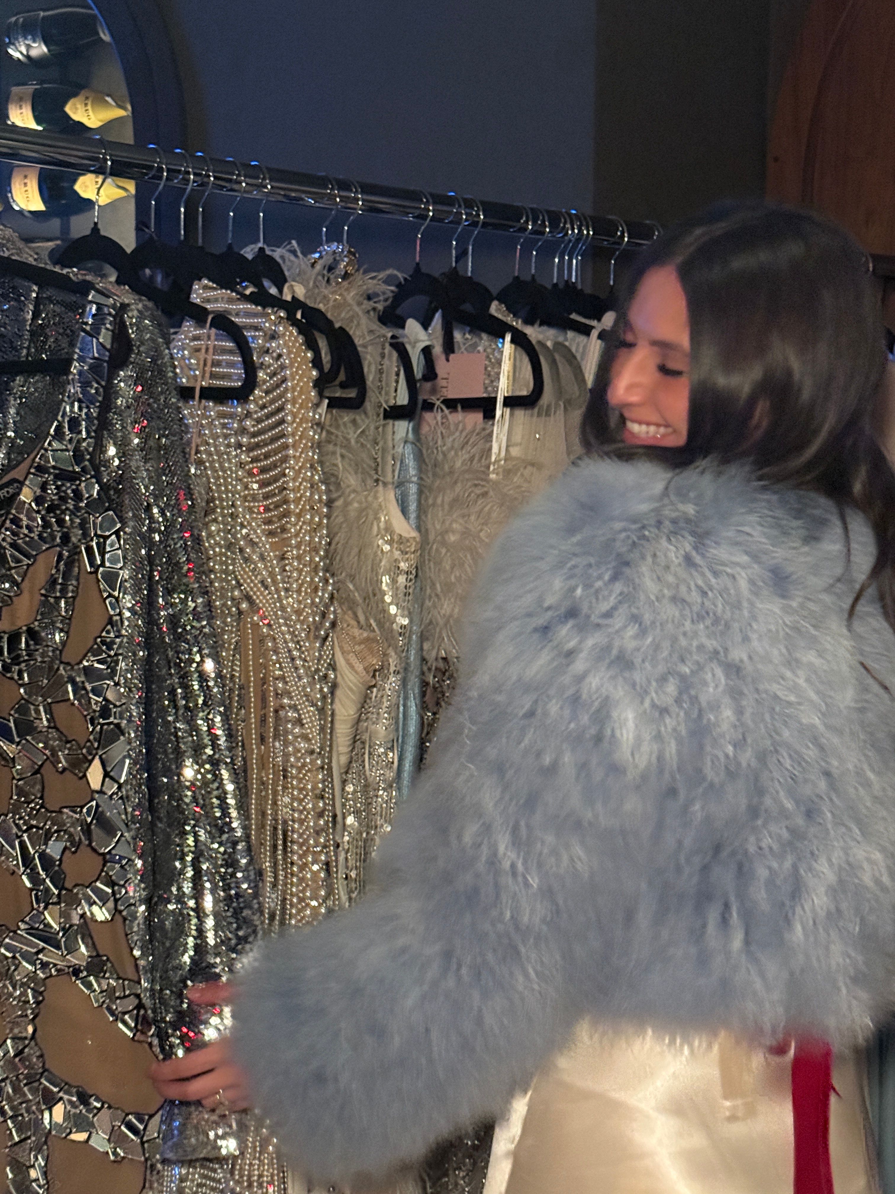 Guest in a pale blue feathered coat browses sparkling vintage couture at the Something Blue NYBFW soirée.